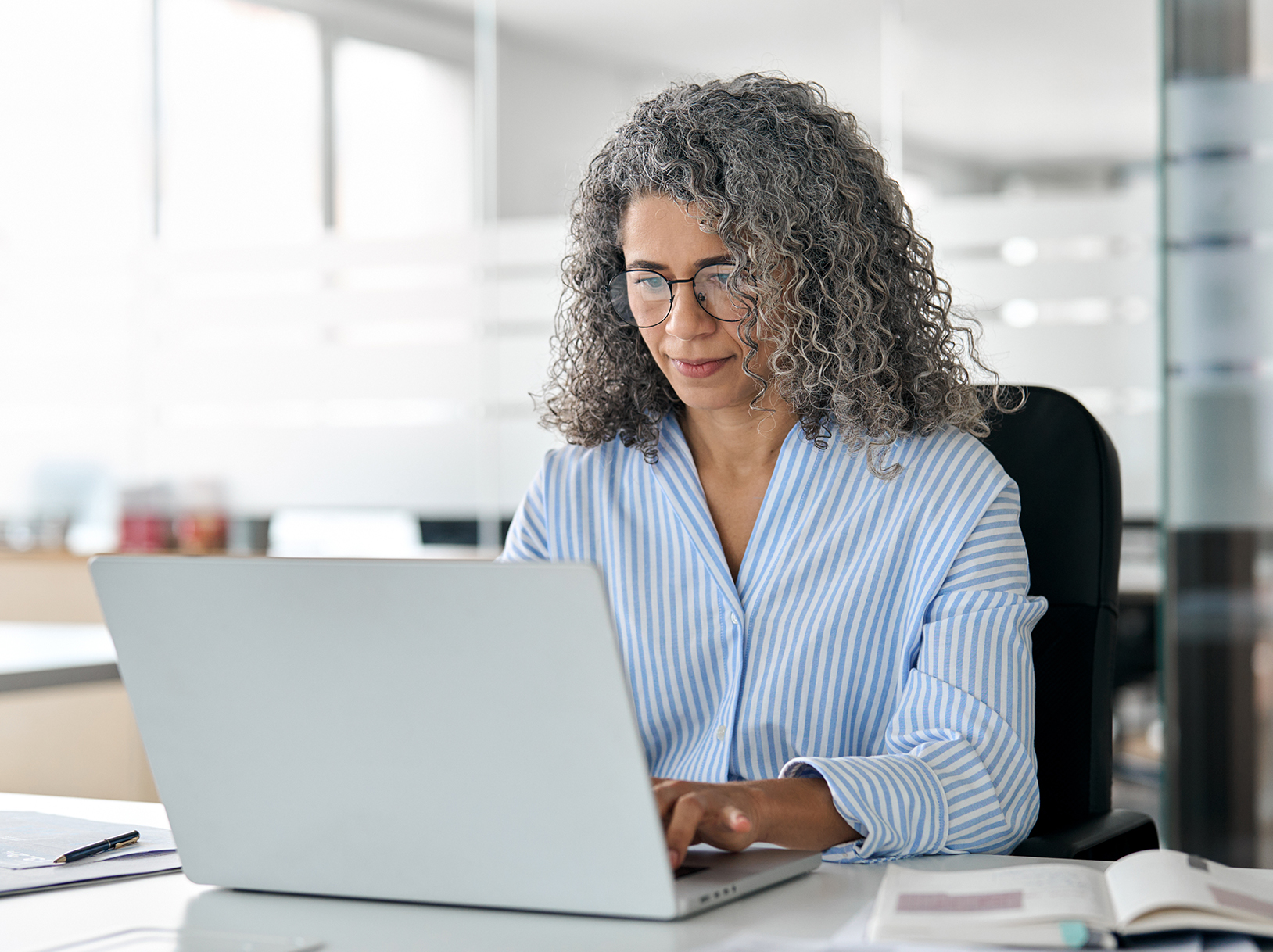 Business woman on computer in bright office space.