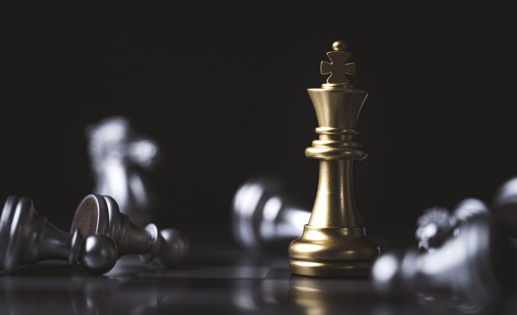 Bronze chess piece with fallen silver pieces around it.
